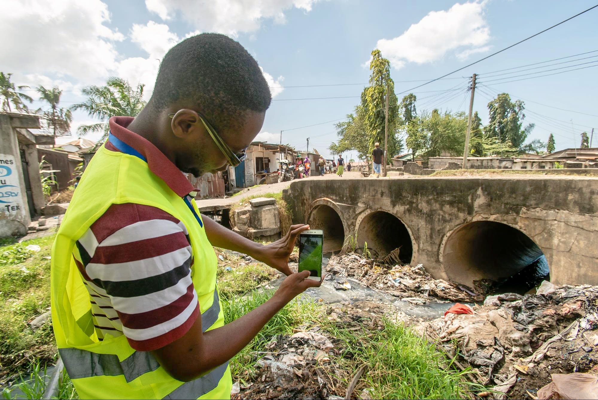 Youth volunteer documents urban drainage conditions in a neighborhood with informal settlements.